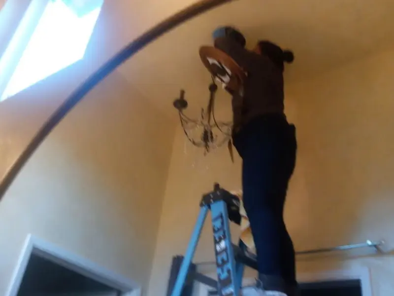Electrician installing a chandelier in a East Point residence